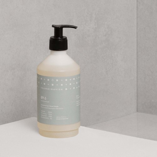 A lotion or soap bottle with a pump on top, plain design, placed on a white surface against a gray wall.