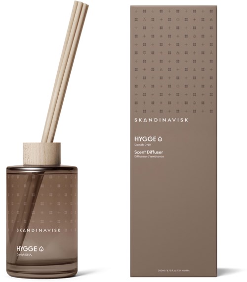 A scent diffuser with wooden sticks is next to its tall brown packaging box, both labeled 'HYGGE' from Skandinavisk.