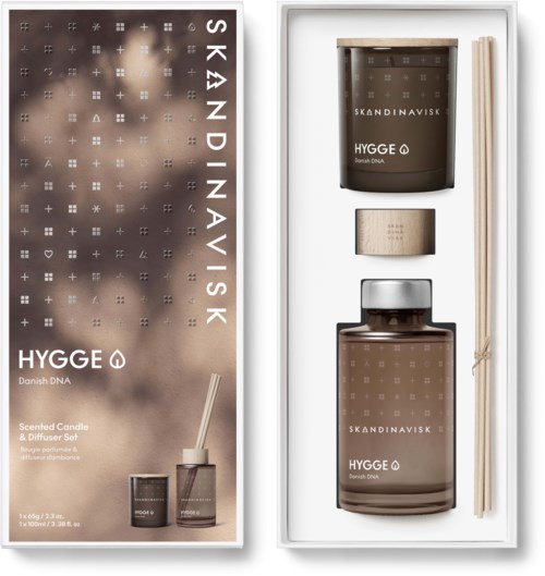 Ein Duftkerze- und Diffuserset mit brauner Verpackung, Stäbchen und einem großen Glas, beschriftet 'HYGGE' und 'Skandinavisk'.