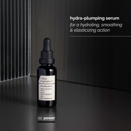 Pieni musta tiptipullo, jossa lukee 'HA-jelly serum', seisoo tummalla pinnalla harjattua harmaata taustaa vasten.