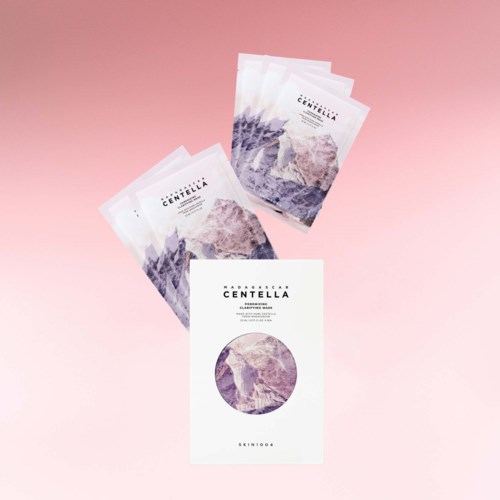 Three face masks and a packet with mountain and purple design on a pink background.