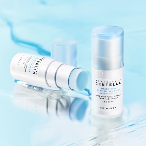 Skincare product bottles, one lying down and one standing on a water surface.