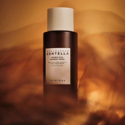 En mørk brun flaske med Madagascar Centella toner og hvit kork, plassert på en varm, skyerik bakgrunn.
