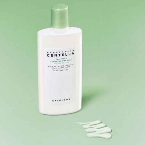 White bottle of Madagascar Centella soothing sun milk with a light green cap, and some white cream on the surface.