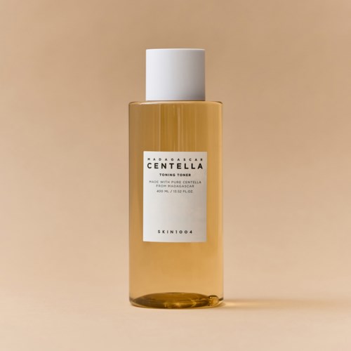A clear bottle with a white cap and label, containing a golden liquid, standing on a plain background.