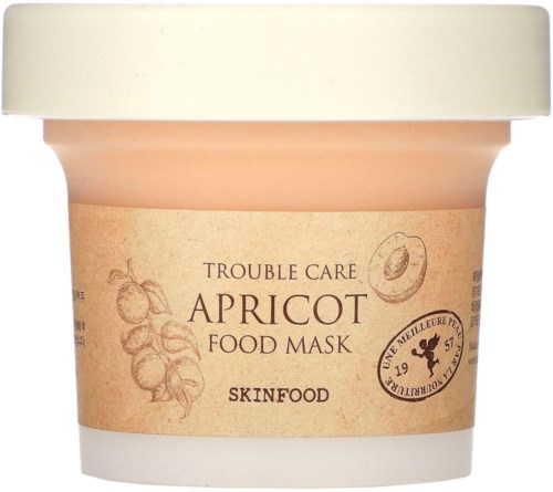 En liten krukke med aprikosmatmaske av SkinFood med beige lokk, har aprikosillustrasjoner og naturlig etikett.