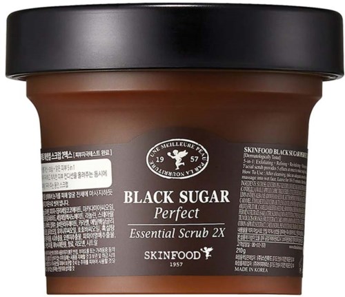 En brun behållare märkt 'Black Sugar Perfect Essential Scrub 2X' från SKINFOOD, tillverkad i Korea, för hudvård.