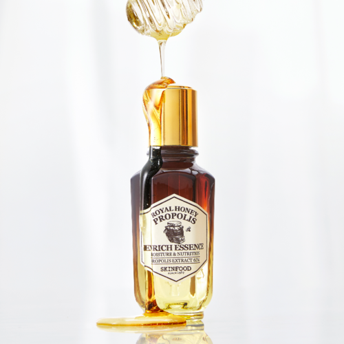 En liten brun flaska med guldkork, honung hälls på den, märkt som Royal Honey Propolis Erich Essence.