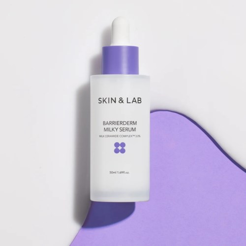 Een witte druppelfles met paarse dop, gelabeld "SKIN & LAB" en "BARRIERDERM MILKY SERUM."