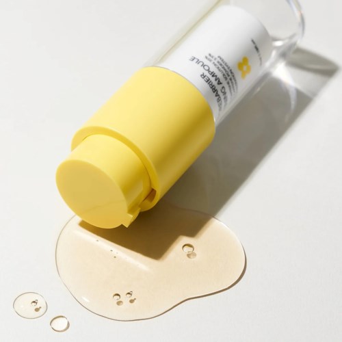 En gul og hvit lotionflaske ligger på siden med lotion som har blitt sølt i nærheten.