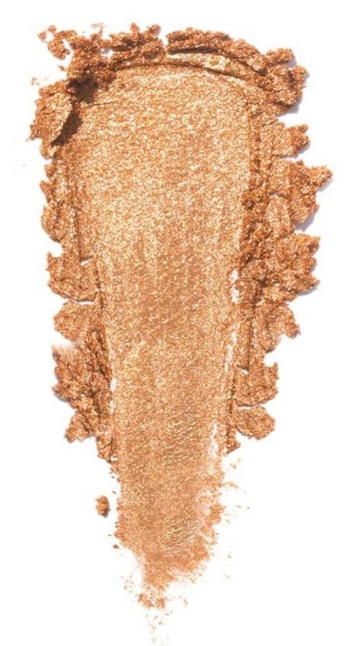En beige- eller guldfärgad makeup-highlighter smulad och utbredd, visar sin glansiga, pudriga textur.