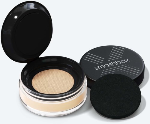 En foundationprodukt med en svamp i en rund svart behållare märkt 'smashbox'.
