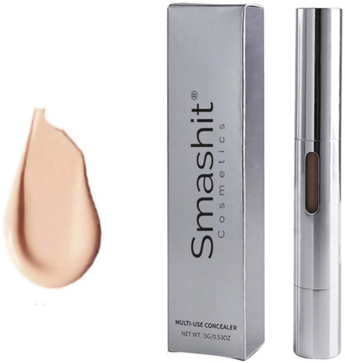 En concealer i sølvemballage med en beige makeup-prøve ved siden af.