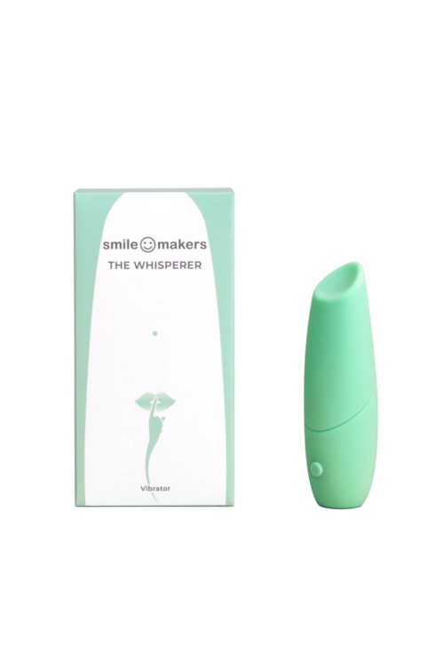A small, green, handheld vibrator next to its box labeled 'Smile Makers The Whisperer'.