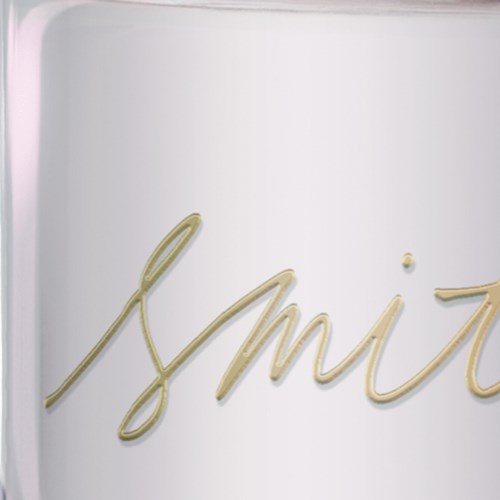 Neon sign spells out "smile" in cursive, mounted on a plain white wall.