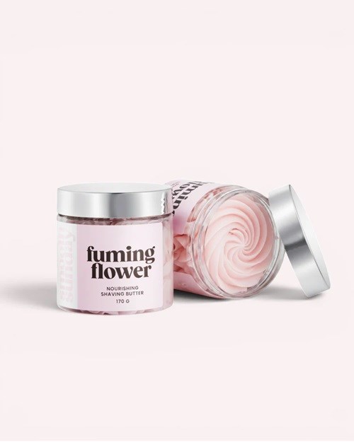 Två burkar av Fuming Flower närande rakbalsam, en öppen som visar rosa smör, mot en ljus rosa bakgrund.