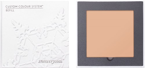 Bildet viser en sminkkompakt med beige pudder inne, og emballasjen har en snøfnugg-design.