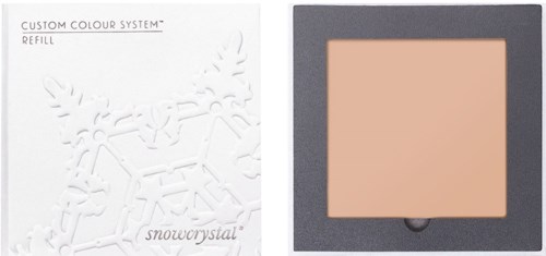 En sminkkompakt i svart eske med en ferskenfarget blush, med emballasje som har et snøfnuggdesign.