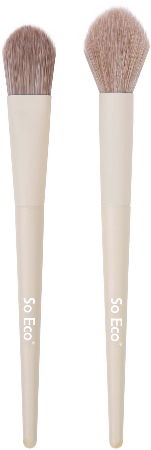 Two makeup brushes with beige handles and soft, light brown bristles stand upright.