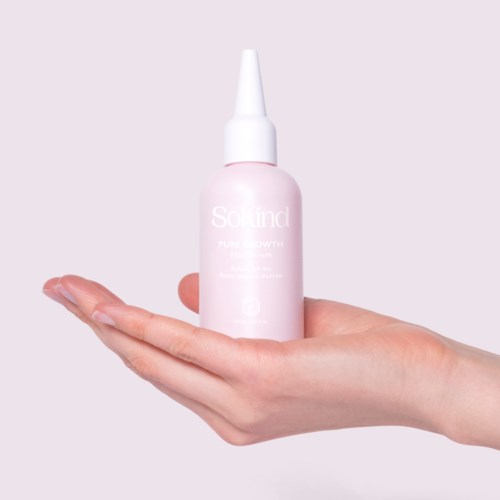 Een hand houdt een roze fles met een witte tuit, waarschijnlijk een huidverzorgings- of schoonheidsproduct.