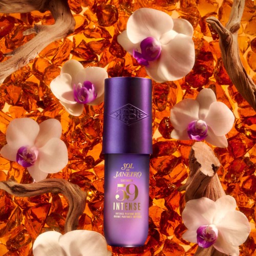Violetti pullo Sol Janerio 59 Intense -tuoksua, ympärillä valkoisia orkideoita ja oransseja koristekiviä.