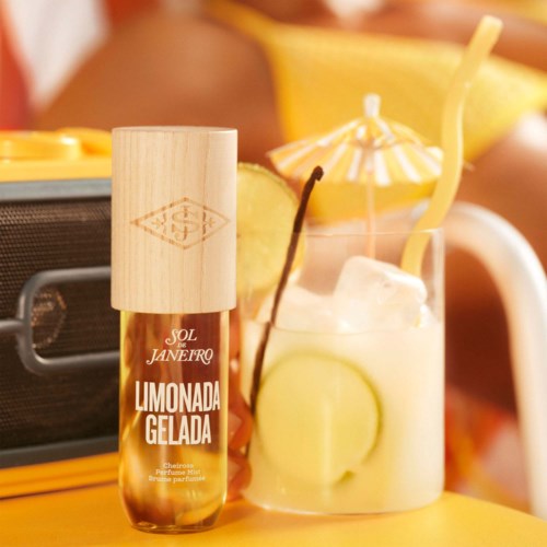 Kleine fles met label Limonada Gelada naast een glas met citroen en rietje, op een gele ondergrond.