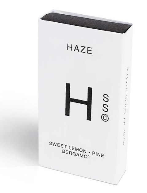 En vit box med svart text och symboler, listar doftnoter av citron, tall, bergamot och har ett stort H.