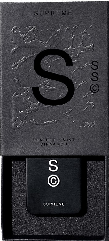 En svart box med ett stort 'S'. Den visar ord: 'SUPREME', 'LEATHER MINT CINNAMON', och mindre 'S' och cirkulerat 'C'.