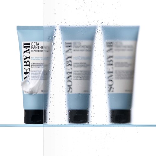 Drie blauwe tubes met witte labels en zwarte doppen, gelabeld als Beta Panthe Repair Body, staan met water spat eromheen.