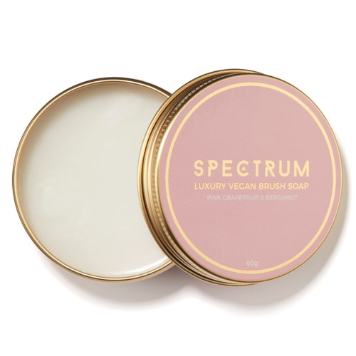 Ympyrän muotoinen kansi, vaaleanpunainen ja kultainen, merkinnällä Spectrum Vegan Brush Soap, avattuna näytteille saippua.