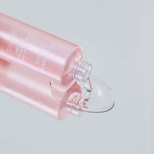 Eine pinke Flasche gießt eine klare Flüssigkeit auf eine Oberfläche.
