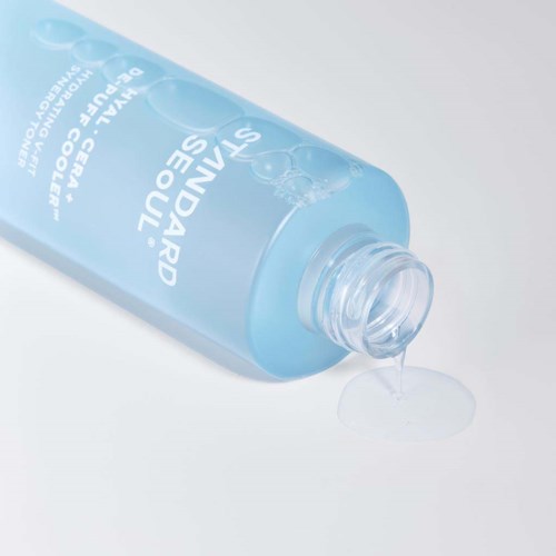 Eine blaue Flasche mit Reinigungswasser, aus der Wasser tropft, und Blasen auf dem Etikett.