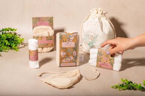 Olika naturliga hudvårds- eller kosmetikaprodukter med förpackningar, en liten tygpåse och växter i bakgrunden.