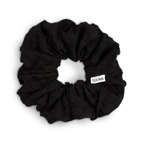 A black fabric scrunchie with a white tag that says SUI AVA.
