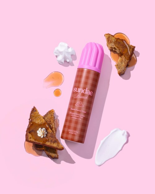 En rosa behållare som heter Sundae finns bland bitar av paj, vispgrädde och sås på en rosa bakgrund.
