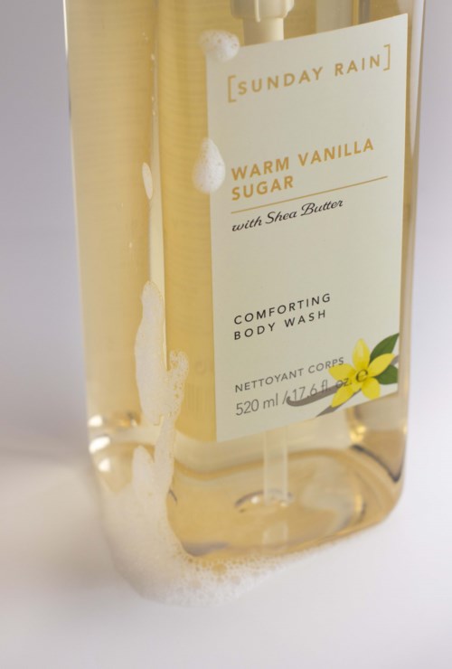 Clear body wash bottle with a label that says Warm Vanilla Sugar and a yellow flower illustration.
