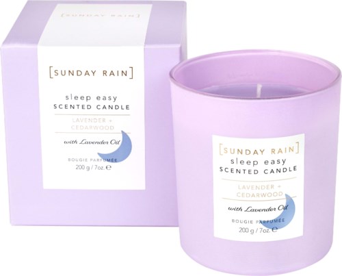Lavendel og cedertræsduftende lys i en lilla beholder med æske, mærket Sunday Rain sleep easy.
