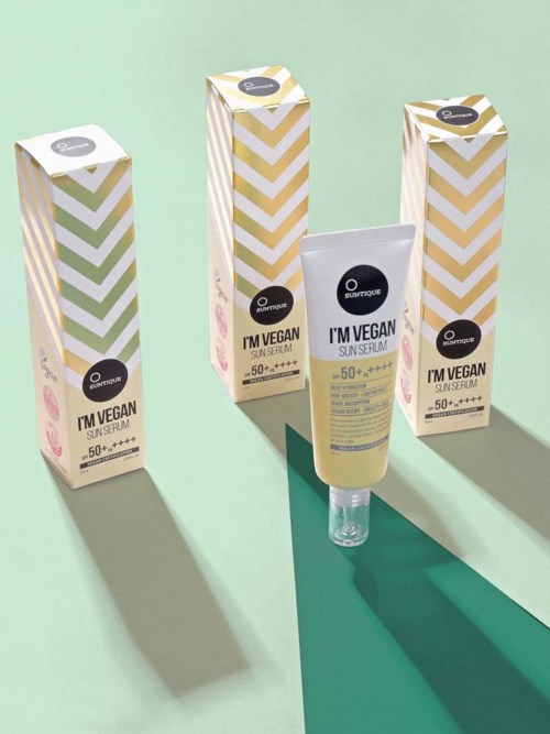 Three boxes and a tube of vegan sun serum with SPF 50 on light green and teal background.