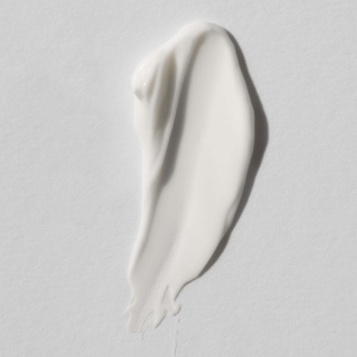 En vit kräm eller lotion utsmetad på en vit bakgrund, visar textur och släthet.