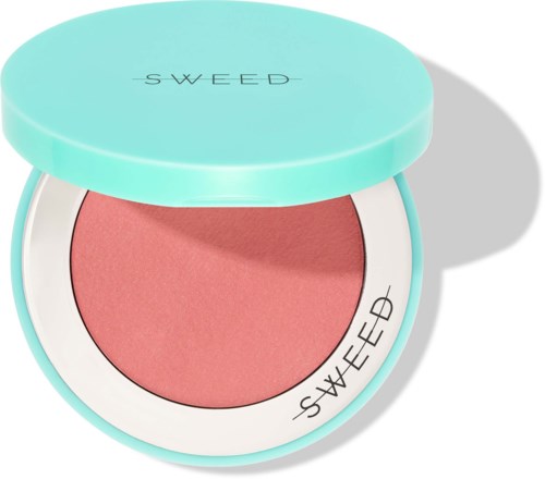 Een roze blush in een ronde, lichtblauwe compact met witte rand en zwarte tekst. De deksel is open.