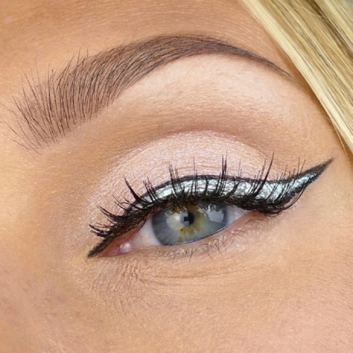 Close-up van een menselijk oog met heldere make-up, lange wimpers en strakke eyeliner. Blond haar dichtbij.