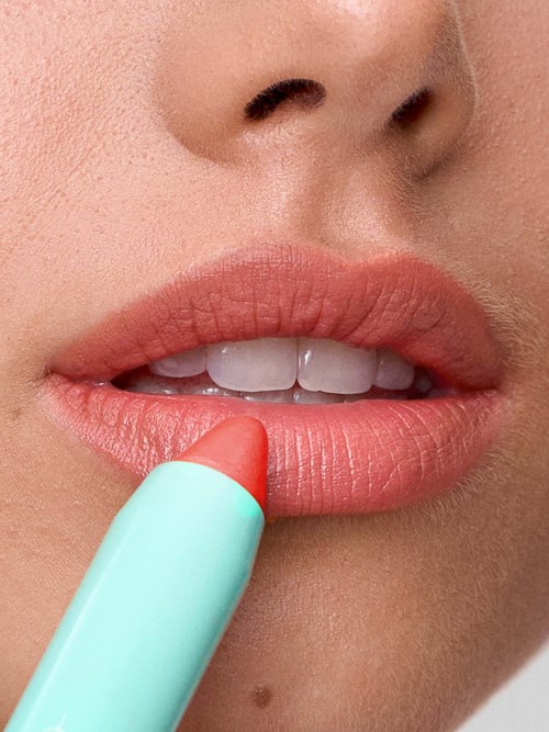 Close-up of lips being colored with lipstick by a person.