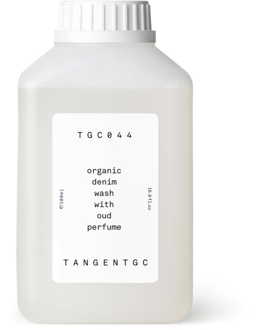 Witte fles met etiket die tekst toont over biologische denimwas, parfum en productcode TGC044.