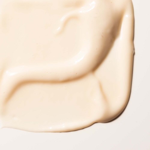 Krämig, slät substans spridd på en yta, möjligen lotion eller hudvårdsprodukt.