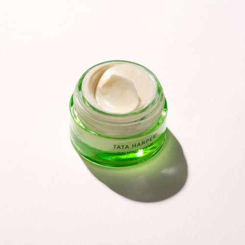 A small round container with cream inside, labeled Tata Harper, on a white background.