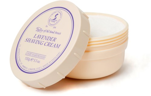 A small round container of lavender shaving cream, with the lid partially open, showing the white cream inside.