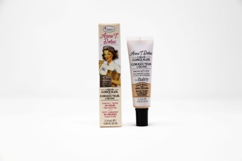En tube og æske med flydende concealer til at dække hudfejl, med retrostil på emballagen og en vintageillustration.