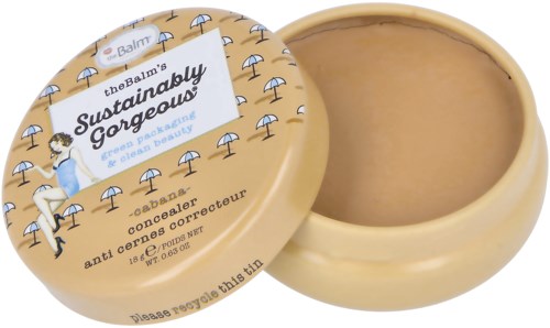 En rund boks av theBalm's Sincerely Gorgeous concealer, med et lysebrunt lokk og et bilde av kvinner som slapper av under parasoller.
