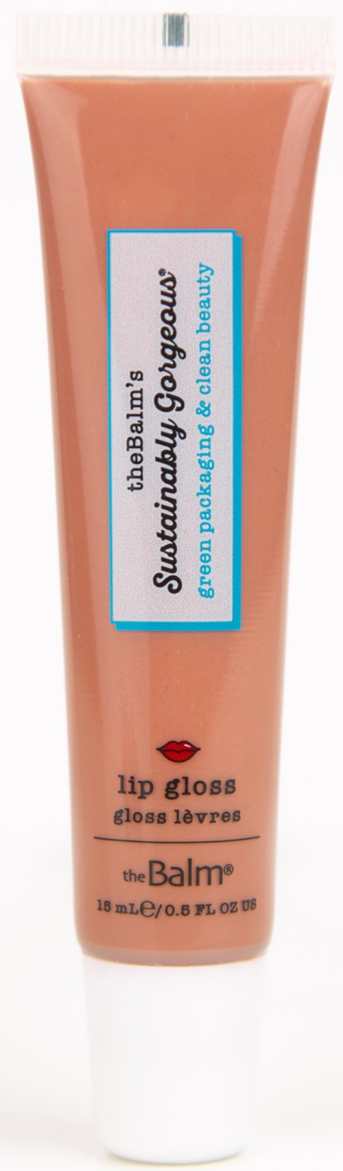 En ferskenfarvet tube med lip gloss fra theBalm, med en blå og hvid etiket og et rødt læbesymbol.