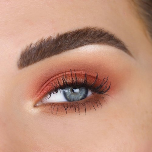 Nærbillede af en kvindes øje med makeup, inklusive øjenskygge, eyeliner, mascara og veldefineret bryn.